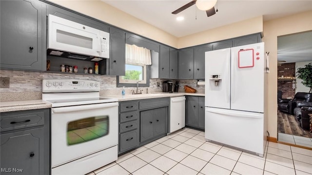 kitchen with a sink, white appliances, gray cabinets, and light countertops