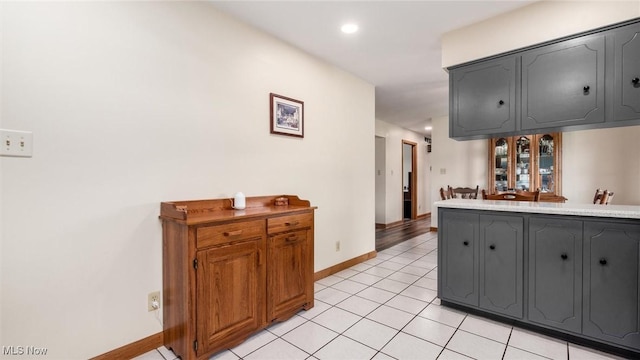 kitchen featuring light tile patterned floors, baseboards, gray cabinetry, and recessed lighting