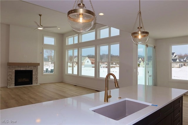 kitchen featuring light wood finished floors, decorative light fixtures, light countertops, a sink, and recessed lighting