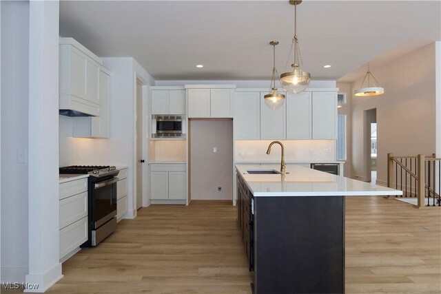 kitchen featuring sink, white cabinets, stainless steel appliances, and an island with sink