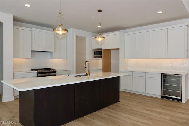 kitchen with light wood finished floors, white cabinets, wine cooler, a sink, and stainless steel range with gas stovetop