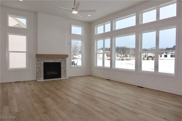 unfurnished living room featuring ceiling fan, light hardwood / wood-style flooring, a healthy amount of sunlight, and a fireplace