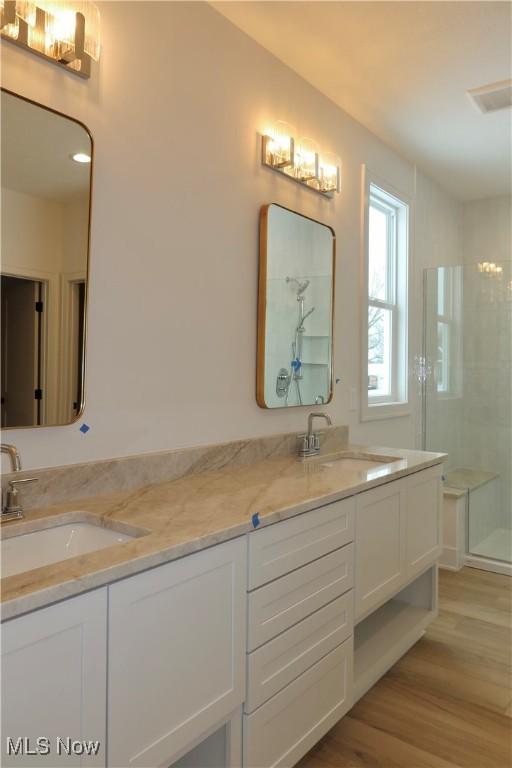 bathroom with wood-type flooring, an enclosed shower, and vanity