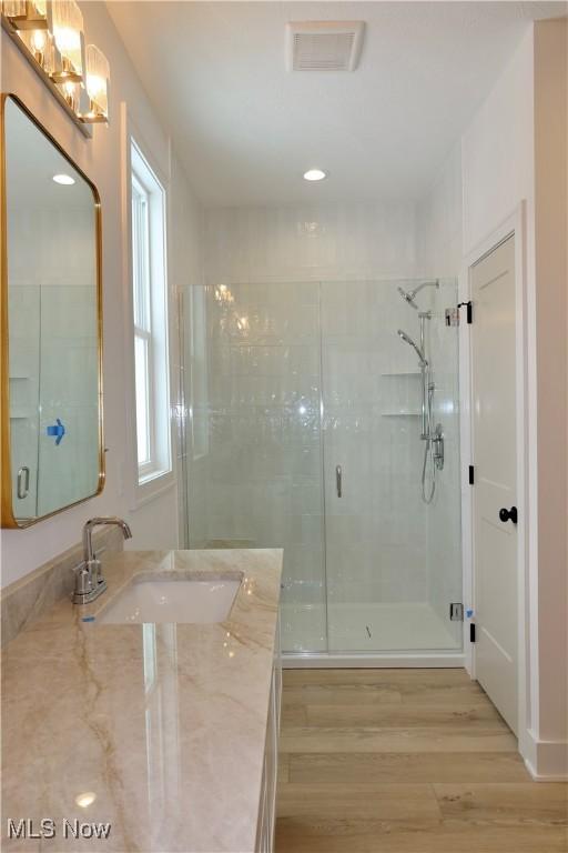 bathroom with vanity, hardwood / wood-style flooring, and a shower with door