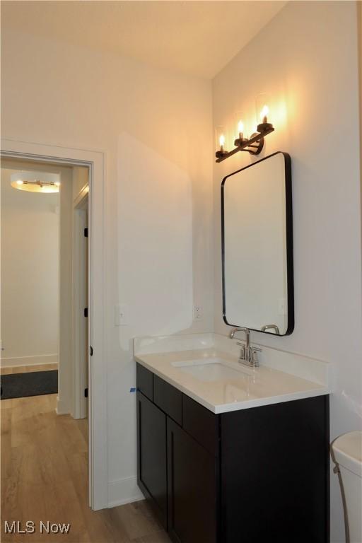 bathroom with wood-type flooring, toilet, and vanity