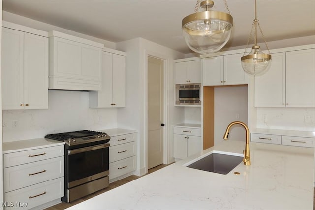 kitchen featuring light stone counters, stainless steel appliances, a sink, white cabinets, and decorative light fixtures