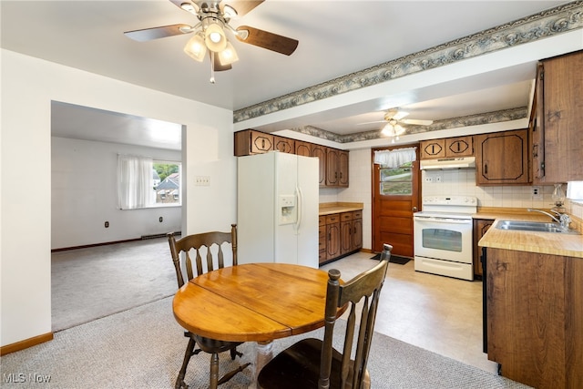 dining area with sink, light carpet, and ceiling fan