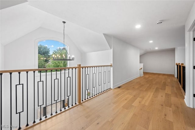 hallway featuring baseboards, lofted ceiling, recessed lighting, an inviting chandelier, and wood finished floors