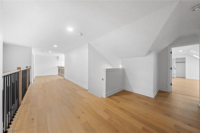 bonus room with baseboards, lofted ceiling, and light wood finished floors