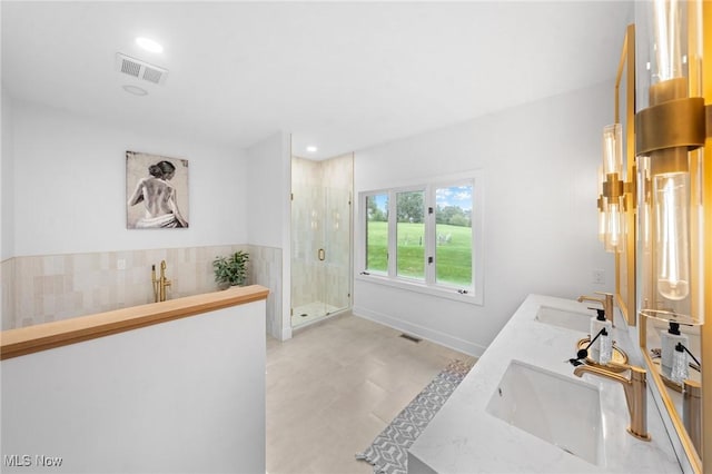 bathroom featuring double vanity, visible vents, a stall shower, and a sink