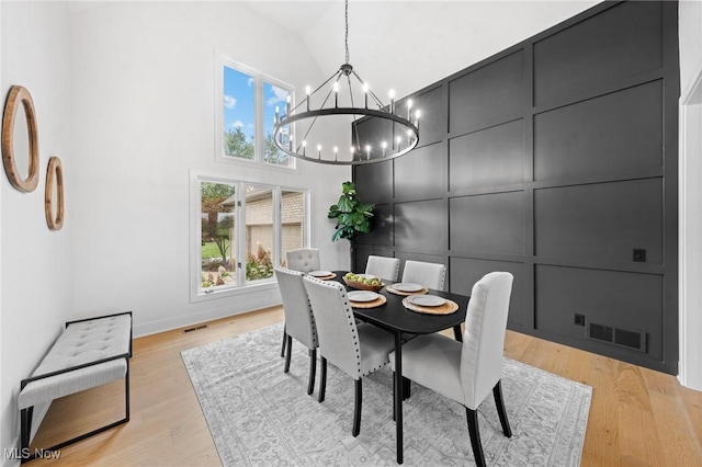 dining room featuring light wood-type flooring, visible vents, an inviting chandelier, and a decorative wall