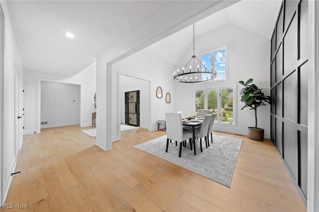 dining area featuring visible vents, baseboards, light wood-style flooring, a notable chandelier, and high vaulted ceiling