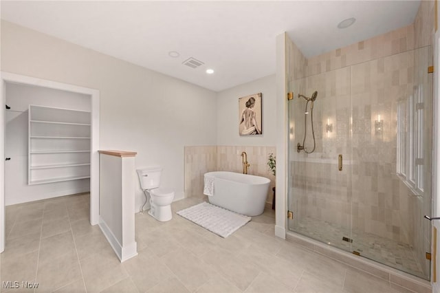 bathroom with tile patterned flooring, visible vents, a shower stall, toilet, and a soaking tub