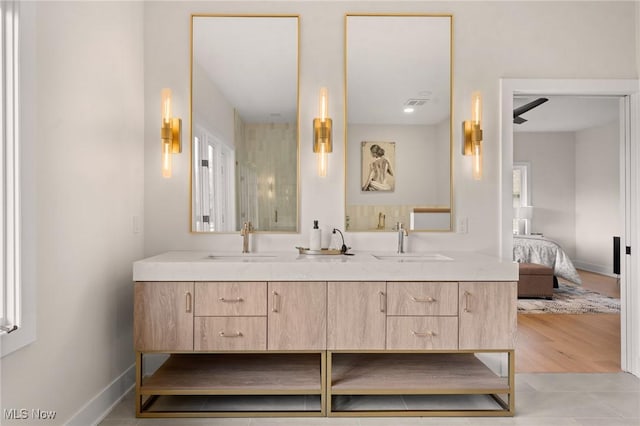 ensuite bathroom featuring a sink, baseboards, ensuite bathroom, and double vanity