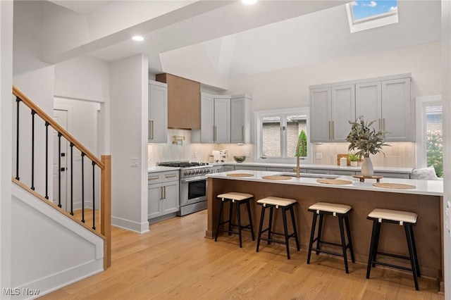 kitchen with light wood-style flooring, stainless steel range, a breakfast bar, and light countertops