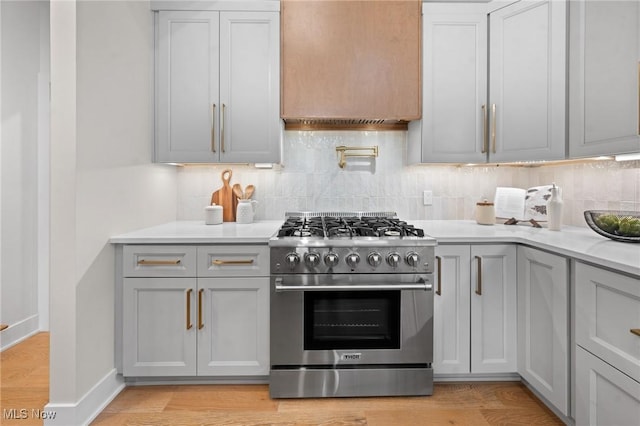 kitchen featuring decorative backsplash, gray cabinetry, high end stainless steel range, and light countertops