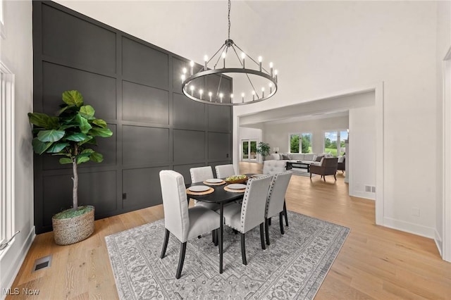 dining room with visible vents, an inviting chandelier, light wood-style flooring, and a decorative wall