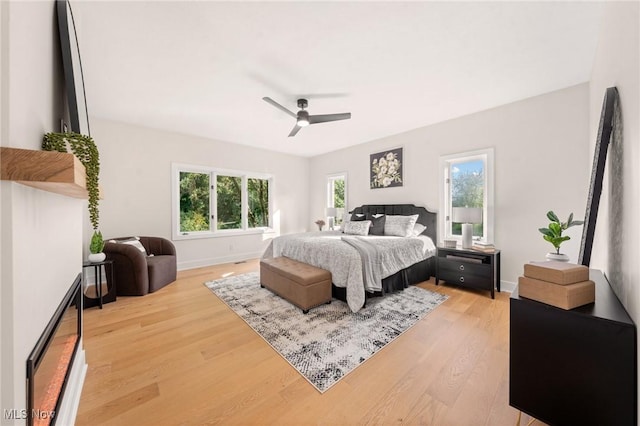 bedroom featuring baseboards, light wood-style floors, and ceiling fan