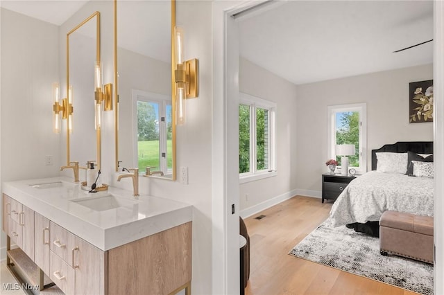 bedroom featuring a sink, visible vents, baseboards, and light wood finished floors