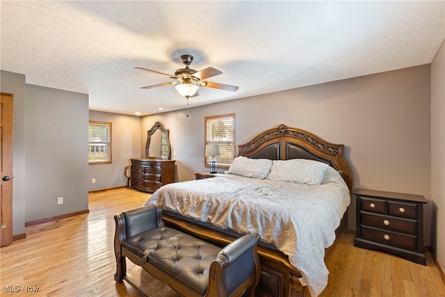 bedroom with ceiling fan, a textured ceiling, and light hardwood / wood-style floors