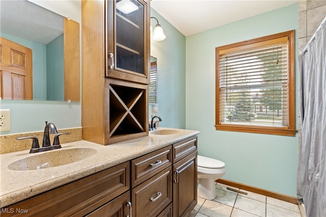 bathroom with tile patterned flooring, toilet, and double sink vanity