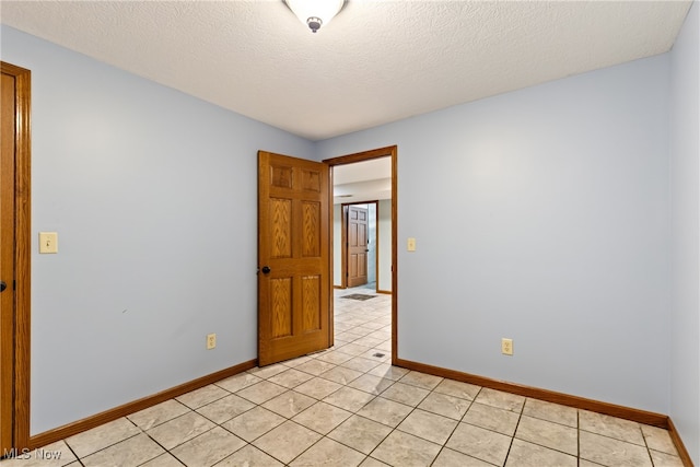 tiled empty room with a textured ceiling