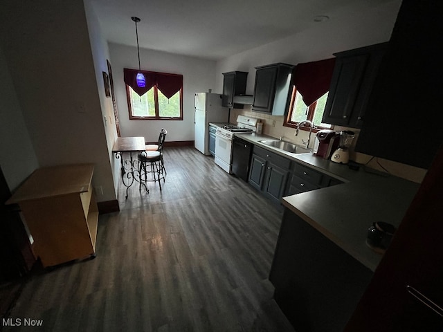 kitchen with hanging light fixtures, sink, white appliances, and dark wood-type flooring