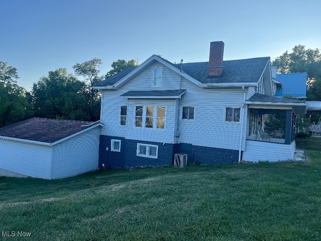 back of property featuring a lawn and central AC