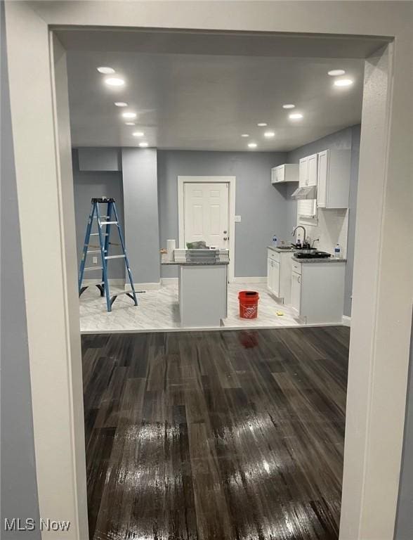 kitchen featuring baseboards, a center island, wood finished floors, and white cabinets