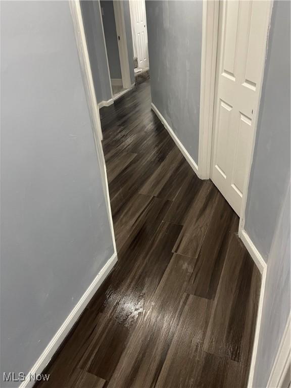 hallway featuring dark wood-type flooring and baseboards