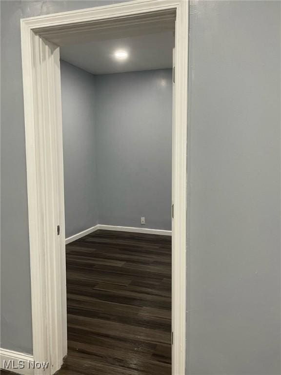 spare room featuring baseboards and dark wood-style floors