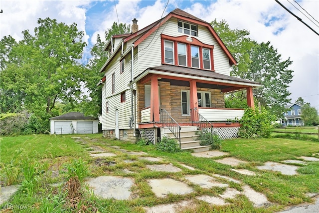 view of front facade featuring a garage, a front lawn, an outbuilding, and covered porch