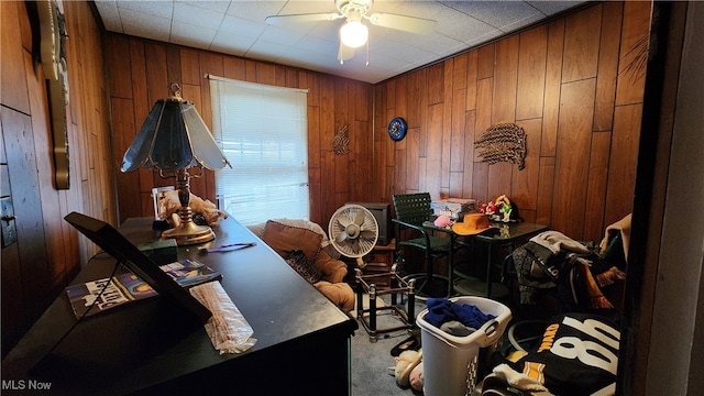 interior space with wood walls, carpet flooring, and ceiling fan