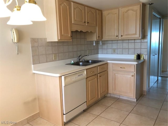 kitchen featuring light brown cabinets, white dishwasher, light countertops, a sink, and light tile patterned floors