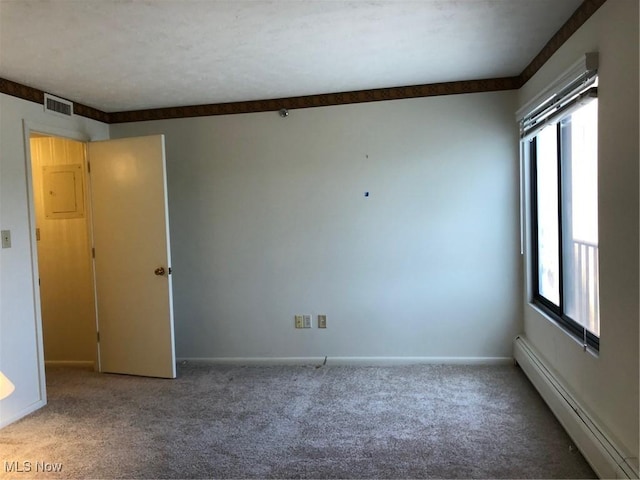 empty room featuring a wealth of natural light, baseboard heating, carpet flooring, and visible vents