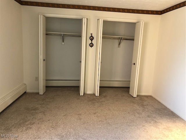 unfurnished bedroom with carpet floors, multiple closets, and a baseboard radiator