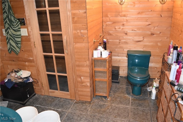 bathroom featuring tile patterned flooring, wood walls, and toilet