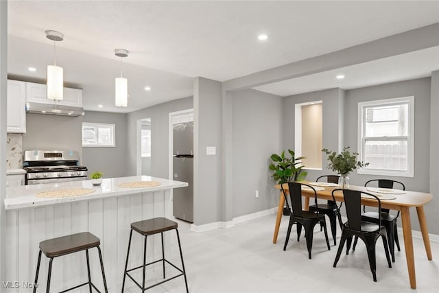 kitchen featuring hanging light fixtures, light stone countertops, tasteful backsplash, white cabinetry, and stainless steel appliances