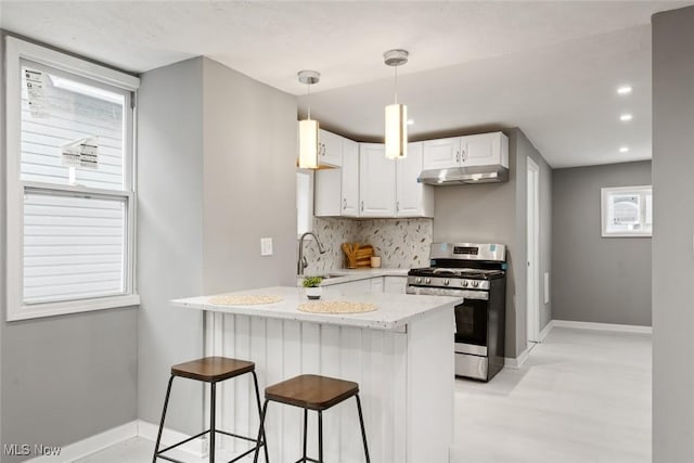 kitchen featuring white cabinets, sink, stainless steel gas range, decorative backsplash, and kitchen peninsula