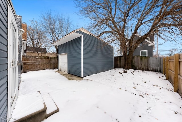 yard covered in snow featuring an outbuilding and a garage