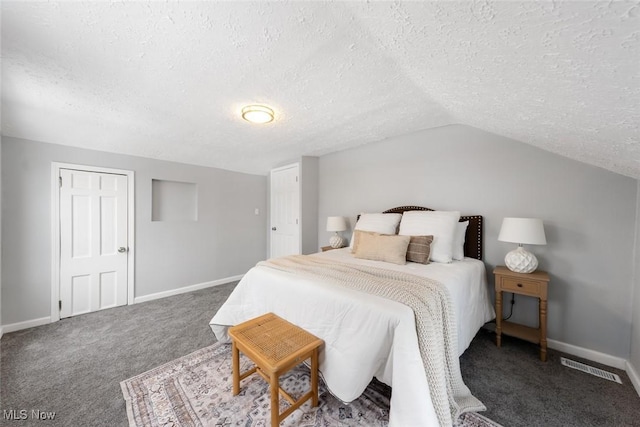 carpeted bedroom with a textured ceiling and vaulted ceiling