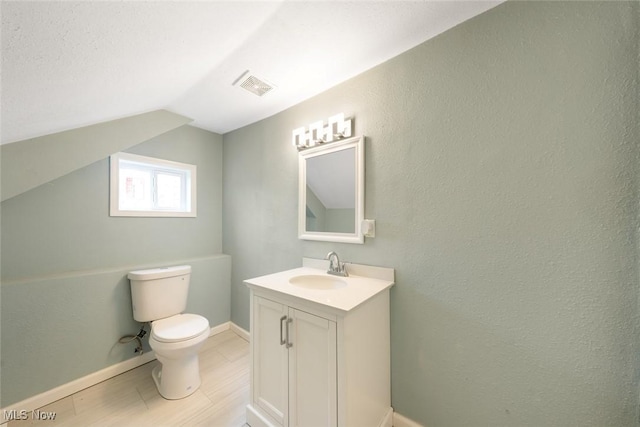 bathroom featuring vanity, lofted ceiling, and toilet