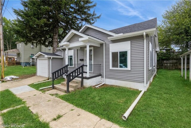 bungalow-style house with a garage, a front yard, and an outdoor structure