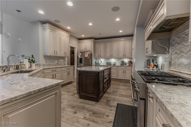 kitchen with light stone counters, tasteful backsplash, stainless steel appliances, light hardwood / wood-style flooring, and sink