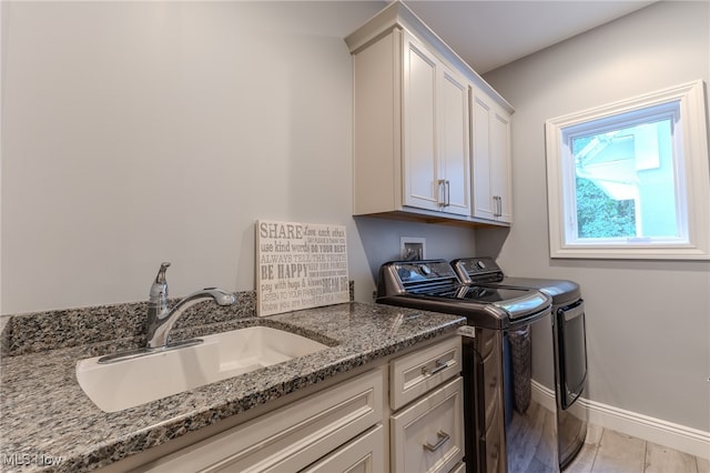 washroom with washer and clothes dryer, sink, light hardwood / wood-style flooring, and cabinets