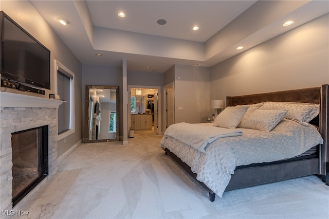 carpeted bedroom featuring a closet, a fireplace, a tray ceiling, and a spacious closet