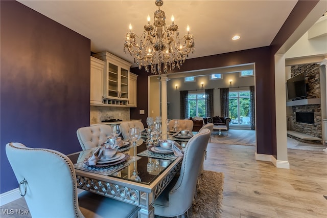 dining area featuring a notable chandelier, light hardwood / wood-style flooring, and ornate columns