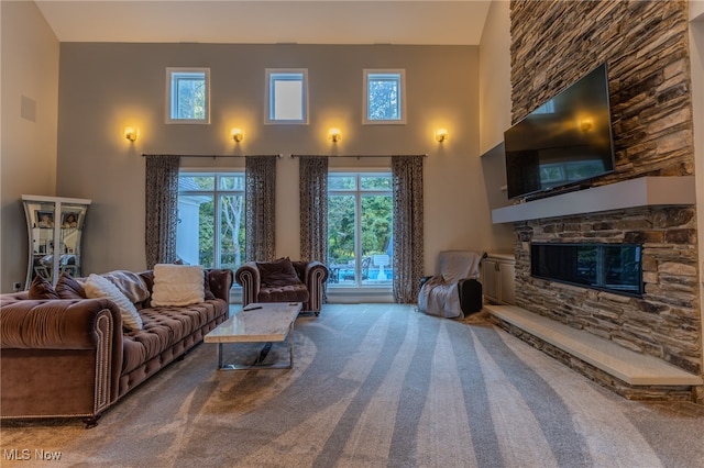 carpeted living room with a fireplace and a towering ceiling