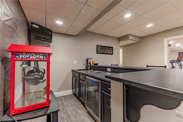 kitchen with a drop ceiling, beverage cooler, light hardwood / wood-style flooring, and sink