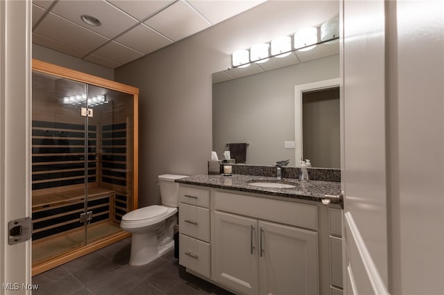 bathroom with a drop ceiling, tile patterned flooring, vanity, and toilet